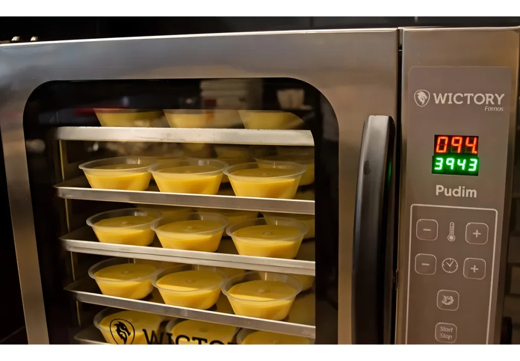 Forno de convecção Wictory WCPP-535D com painel digital carregado com 5 assadeiras de pudim, demonstrando a tecnologia de hidratação sem banho-maria.