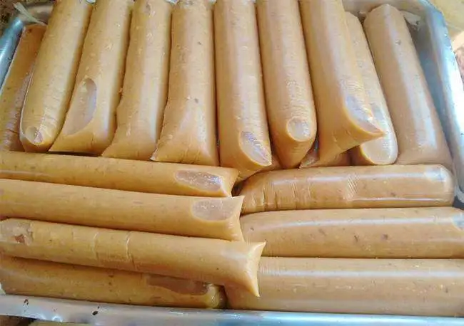 Geladinhos gourmet de coco queimado com coloração dourada característica e pedaços tostados, organizados em uma bandeja para comercialização.