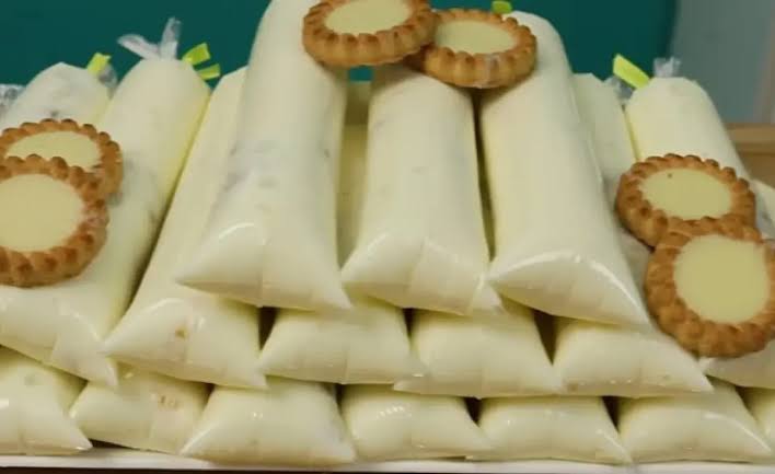Geladinhos gourmet de torta de limão artesanais com camada de biscoito triturado e limões frescos inteiros e cortados sobre uma tábua de madeira.