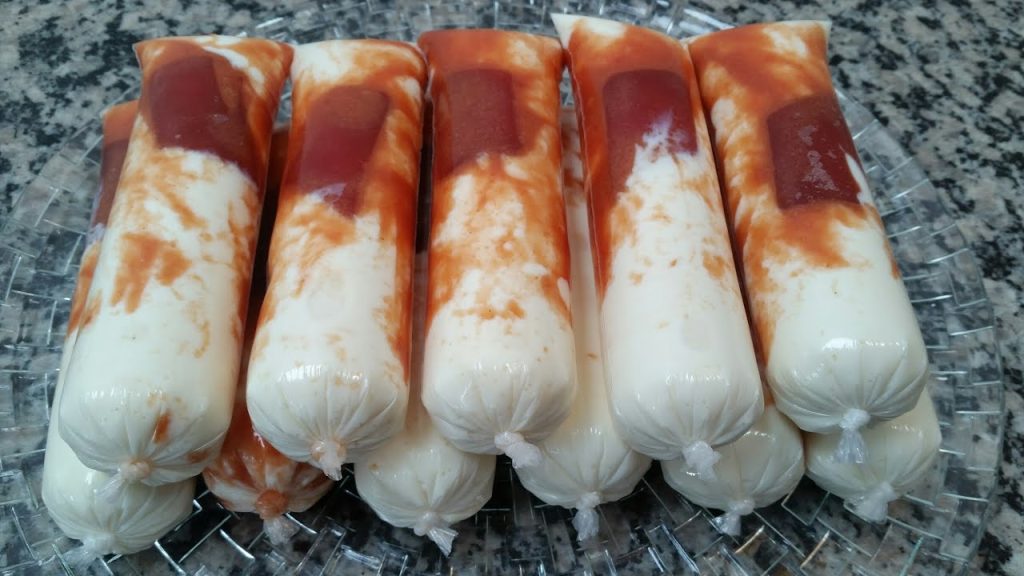 Geladinhos gourmet Romeu e Julieta artesanais recheados com base cremosa de queijo e riscas de goiabada cremosa dispostos em um prato de vidro.