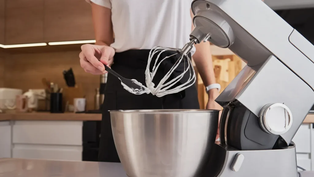 Batedeira planetária premium vermelha, cercada por ingredientes e doces prontos, simbolizando um negócio de confeitaria consolidado.