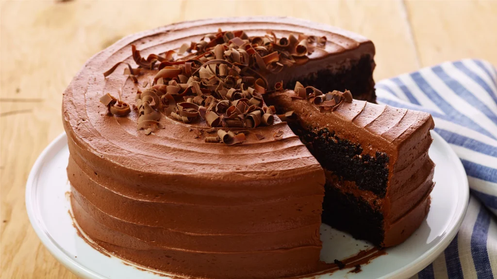 Bolo de chocolate de dois andares com cobertura e recheio cremosos, decorado com raspas de chocolate no topo.