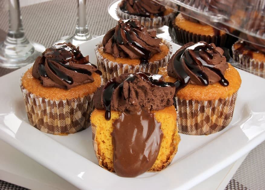 Quatro cupcakes de cenoura com cobertura de brigadeiro cremoso e detalhes de chocolate.