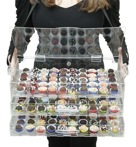 Vários docinhos gourmet variados em forminhas pretas, com diferentes coberturas como M&Ms, amendoim, granulado e coco, dispostos em um expositor transparente para doces.