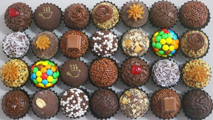 Uma bandeja de docinhos de festa com 30 brigadeiros variados, decorados com granulados, confeitos, coco, M&M's e recheios diversos.