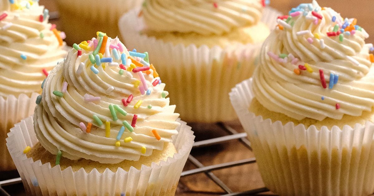 Cupcakes de baunilha recém-assados com massa fofinha e cobertura de chantilly cremoso.