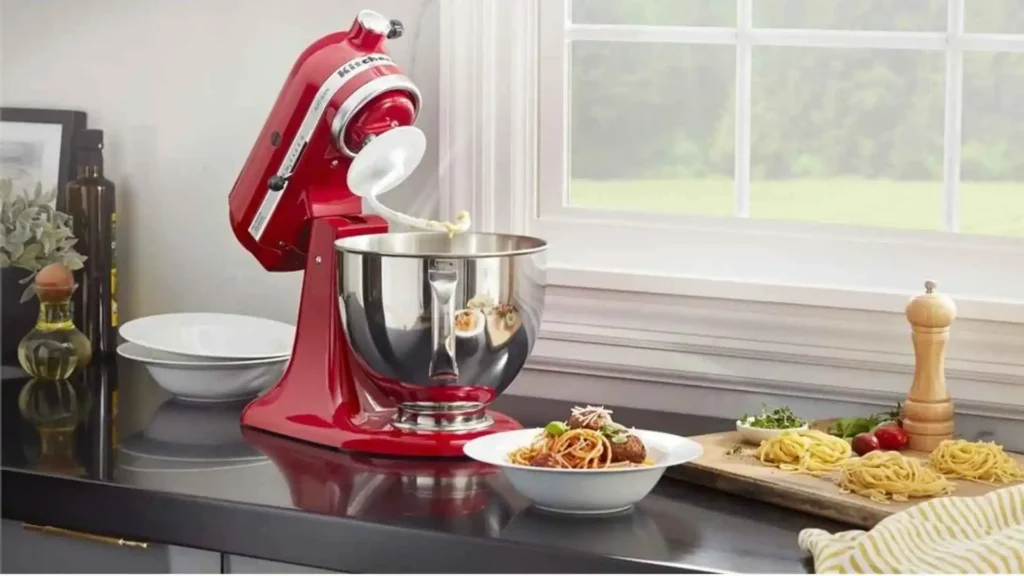 Batedeira KitchenAid Artisan Vermelha (Empire Red) em uma bancada de cozinha, demonstrando o uso do gancho para massas pesadas e sua estrutura robusta em metal.