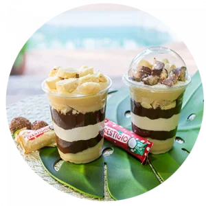 Dois Copos da Felicidade com camadas de coco e chocolate, inspirados no bombom Prestígio. Demonstra a versatilidade de sabores abordados no treinamento.