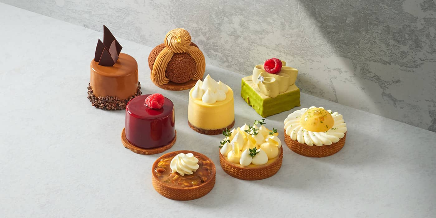 Seleção de mini entremets e sobremesas finas de confeitaria, com glacage espelhado e decorações elegantes.