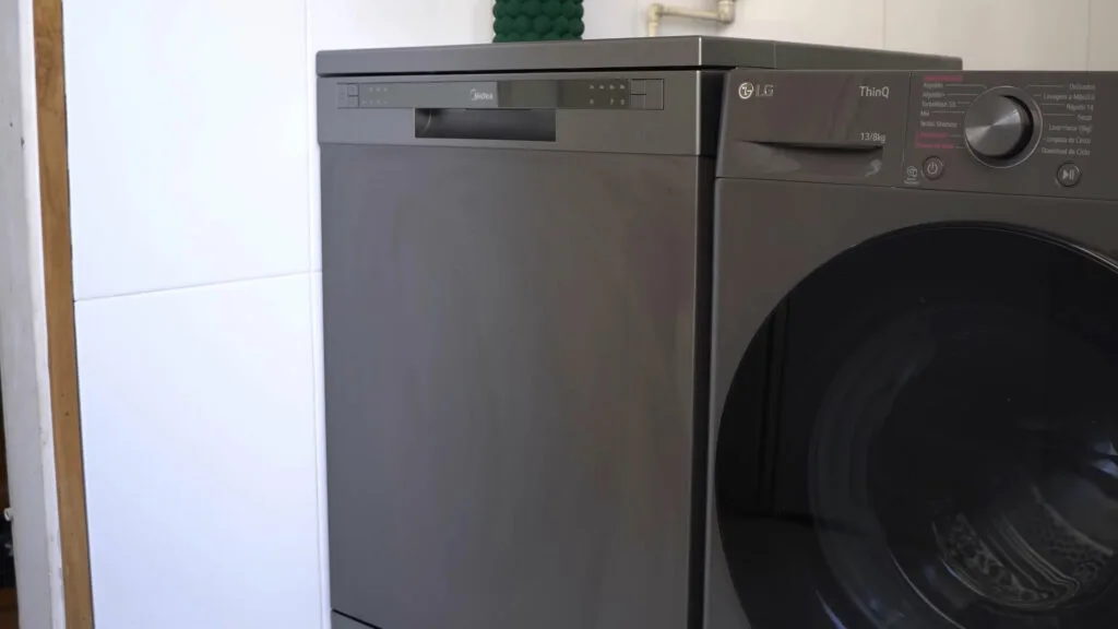 Vista lateral da lava-louças Midea 14 serviços preta instalada ao lado de uma lavadora de roupas, destacando o alinhamento e o acabamento superior do gabinete.