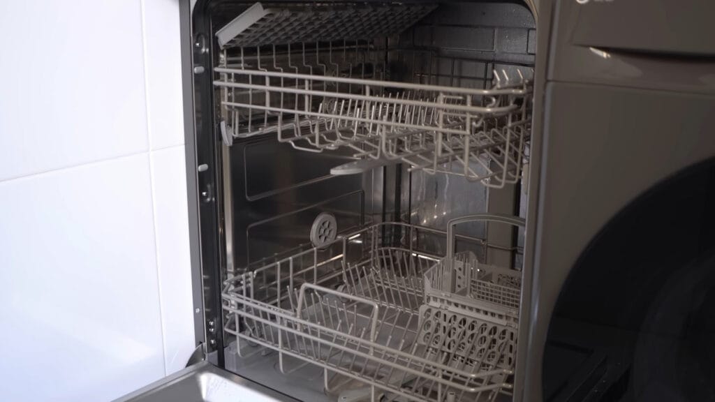 Vista interna da lava-louças Midea 14 serviços aberta, exibindo os dois cestos de louças, o terceiro cesto para talheres no topo e o acabamento em aço inoxidável.