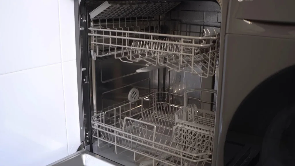 Vista interna da lava-louças Midea 14 serviços aberta, exibindo os dois cestos de louças, o terceiro cesto para talheres no topo e o acabamento em aço inoxidável.