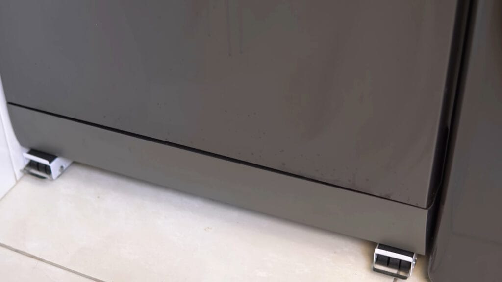 Detalhe da parte inferior da porta da lava-louças Midea 14 serviços preta, mostrando pequenas marcas de uso e respingos comuns no dia a dia de uma cozinha profissional.