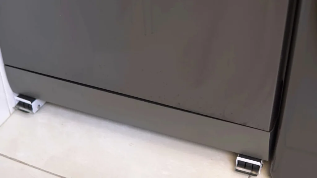 Detalhe da parte inferior da porta da lava-louças Midea 14 serviços preta, mostrando pequenas marcas de uso e respingos comuns no dia a dia de uma cozinha profissional.