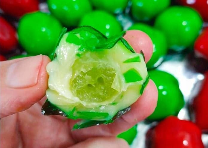 Foto de uma Uva do Amor (bombom recheado) cortada ao meio, mostrando o interior da uva verde e o recheio de brigadeiro branco cremoso.