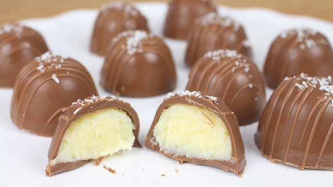 Trufas de chocolate de coco, com uma cortada ao meio para mostrar o recheio branco e macio.