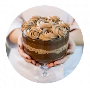 Taça da Felicidade em vidro transparente, recheada com múltiplas camadas de chocolate em diferentes texturas e tons, com decoração de chantilly de chocolate. Uma amostra do que se aprende no curso.