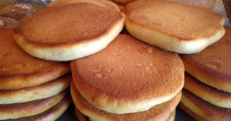 Pilha de bolos de caco dourados e fofinhos, feitos na frigideira, prontos para servir.