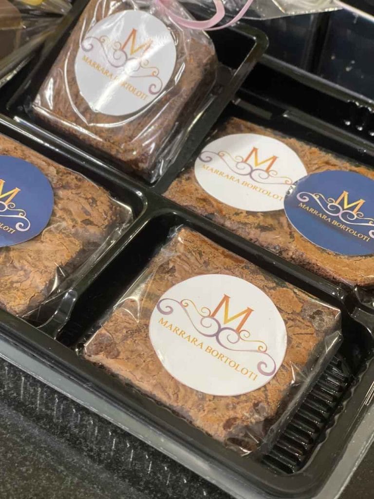 Brownies quadrados embalados individualmente em caixa preta, com selo da marca Marrafa Bortoloti, prontos para venda e delivery