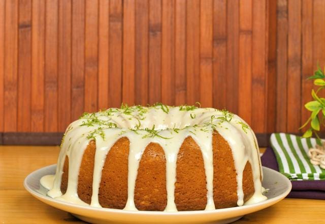 Bolo tipo piscina com cobertura de limão durinha em efeito gotejante (drip cake) sobre o bolo. Demonstra o ponto ideal da cobertura para bolo de limão com leite condensado.