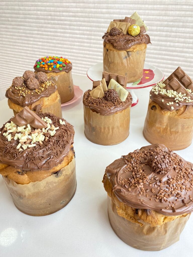 Conjunto de mini-chocotones trufados com decorações gourmet variadas (Kinder Bueno, Brigadeiro, M&Ms), mostrando a diversidade de produtos para venda e a alta lucratividade do cardápio de Natal.