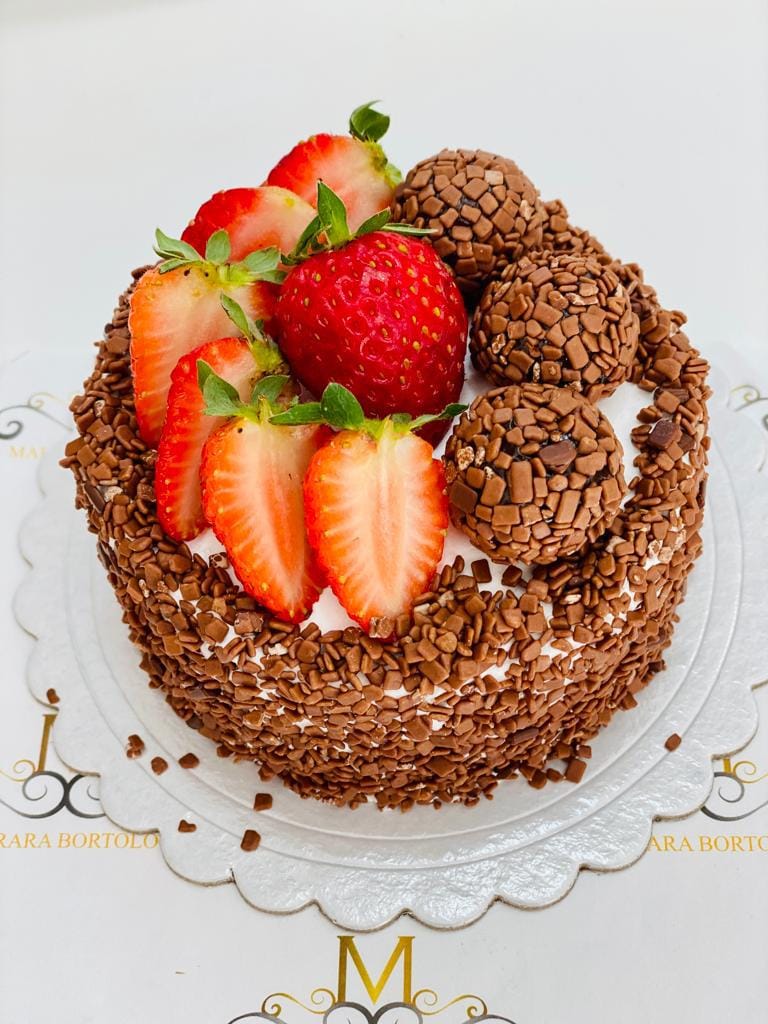 Detalhe de um minibolo gourmet coberto com granulado de chocolate, morangos frescos e brigadeiros gourmet, o acabamento ideal para um bento cake de luxo