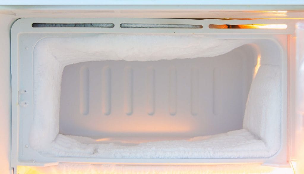 Interior de um freezer com acúmulo excessivo de gelo nas paredes, ilustrando a necessidade de degelo para manutenção da eficiência energética.