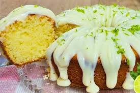 Close-up da cobertura para bolo de limão durinha em efeito gotejante (drip cake) sobre um bolo fofinho, finalizada com raspas de limão.