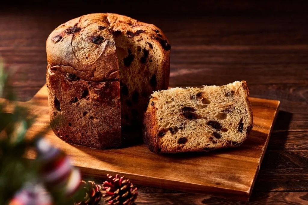 Fotografia de panetone (chocotone) com efeito corte para mostrar a massa fofa e os chocolate chips. O cenário escuro e rústico é ideal para venda por impulso e criação de vídeo viral.