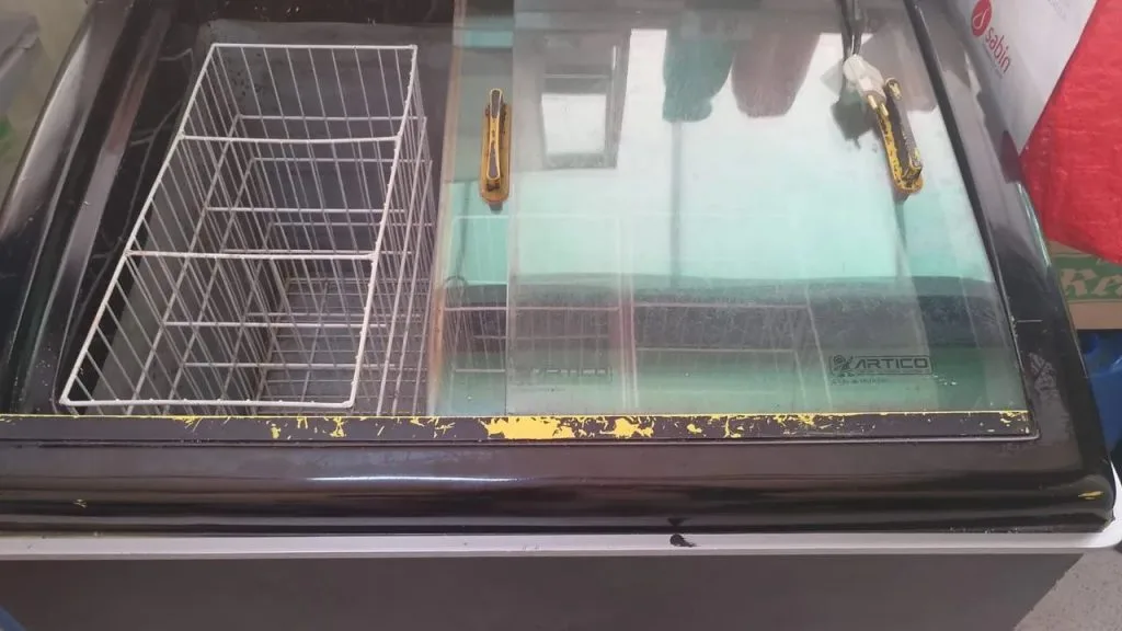 Visão superior de um freezer horizontal com tampa de vidro, exibindo cubetas de sorvete e açaí organizadas em fileiras, demonstrando o controle de estoque e análise de demanda.