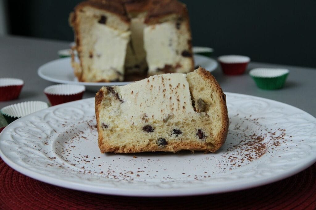Fatia de Panetone Tiramisu Clássico com recheio cremoso de Mascarpone e cacau em pó. A imagem ilustra uma receita gourmet lucrativa, utilizando infusão de café e creme estável.