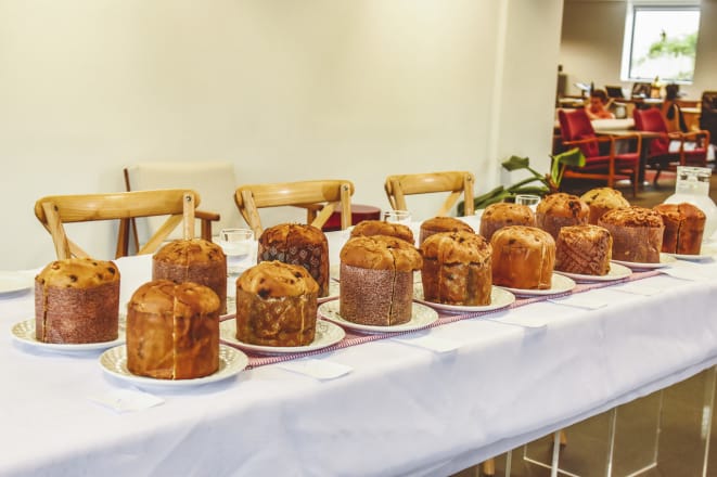 Mesa com diversos panetones gourmet artesanais prontos para venda, representando o portfólio de luxo que constrói Autoridade Premium e garante o retorno do cliente através da fidelização por sabores exclusivos (pistache, tiramisu).