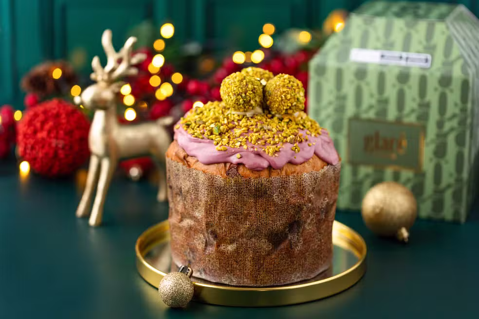 Panetone de Pistache Siciliano com cobertura e granulado de pistache, em um cenário de Natal luxuoso. Uma variação lucrativa gourmet de alto valor agregado, ideal para vendas especiais.