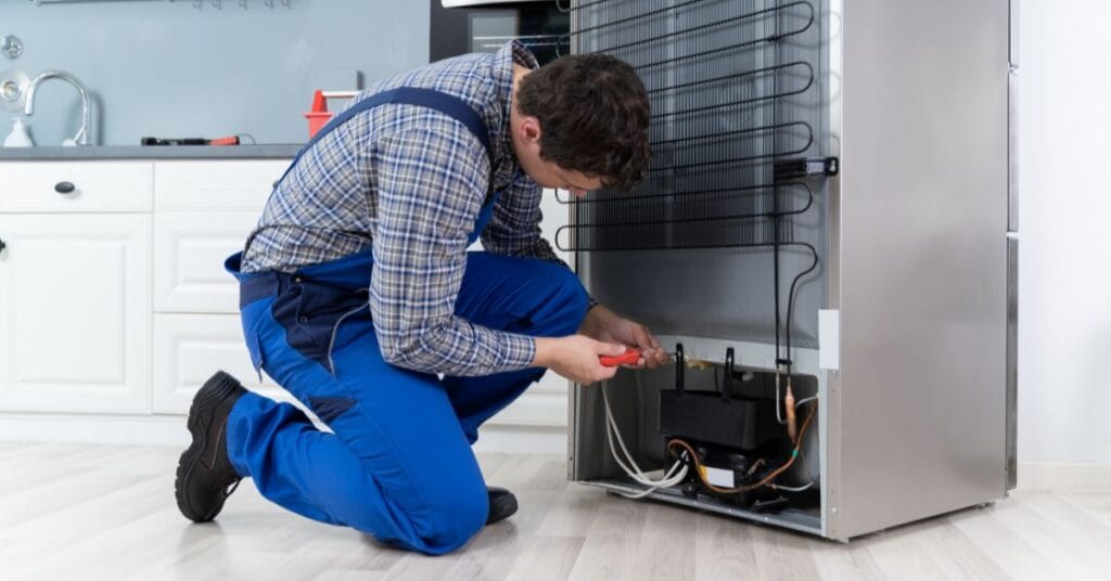 Técnico inspecionando o motor e os componentes internos de um freezer. A imagem ilustra a importância do Checklist do Freezer Econômico para garantir a Eficiência Energética e um investimento rentável para a confeitaria.