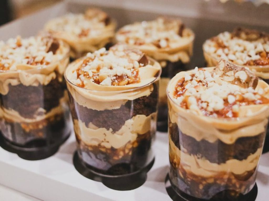 Bolos no Pote Gourmet (sabor caramelo/amendoim) em embalagem profissional. O padrão de qualidade e a variedade que garantem a Lucratividade em Larga Escala, resultado de um rigoroso controle de Validade e Segurança Alimentar.