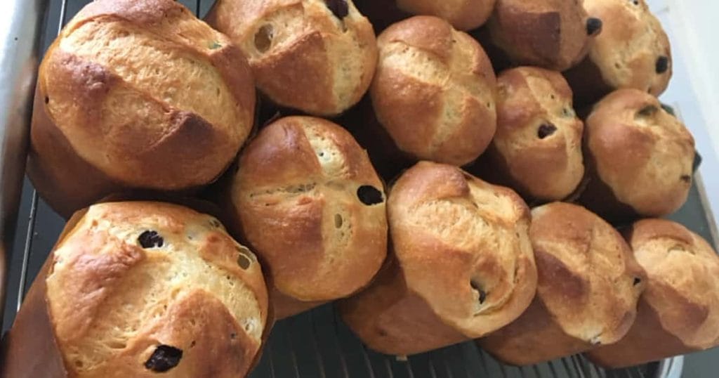 Grande volume de mini panetones caseiros recém-assados em uma grade de resfriamento. A imagem ilustra o sucesso da Massa Base Fofinha e Úmida, que gera Lucro, Fidelização e Vantagem Competitiva no mercado.