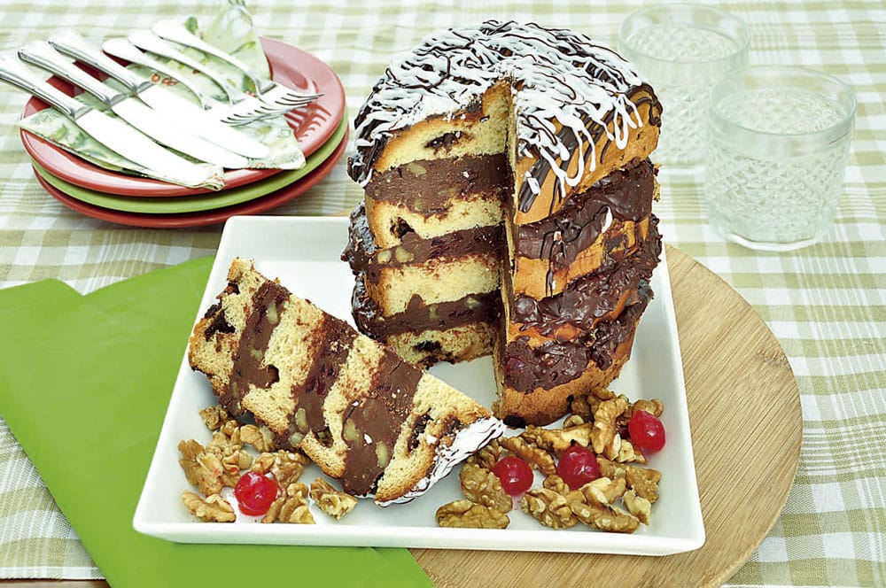 Panetone trufado cortado, mostrando camadas de recheio de chocolate com nozes. O produto de alta complexidade exige armazenamento e congelamento profissional para garantir a validade e o sabor.