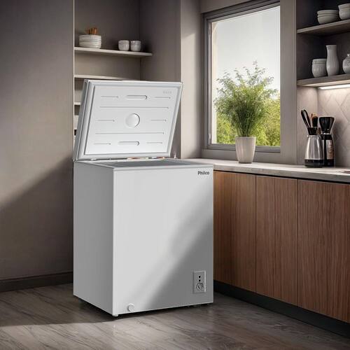 Freezer horizontal branco da marca Philco com a tampa aberta, posicionado em uma cozinha moderna próximo a uma janela, respeitando o espaço de ventilação lateral.