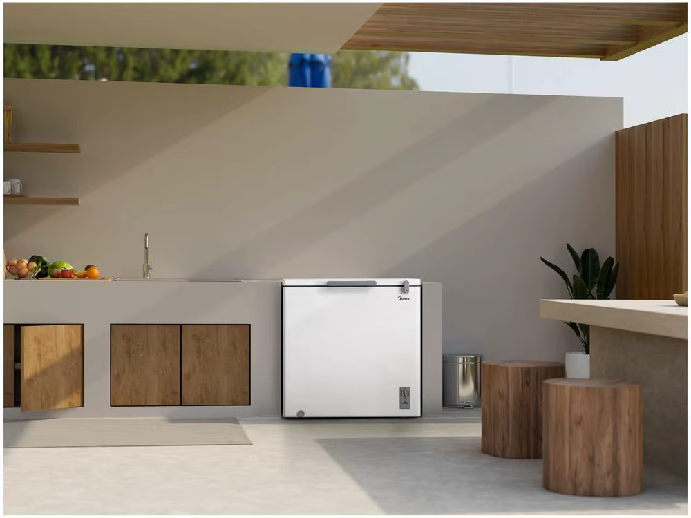 Freezer horizontal branco Midea instalado em uma área gourmet moderna e iluminada, com bancada de concreto e decoração minimalista.
