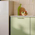Freezer vertical branco posicionado em uma cozinha moderna com armários verdes, ilustrando um eletrodoméstico econômico e bem ventilado.