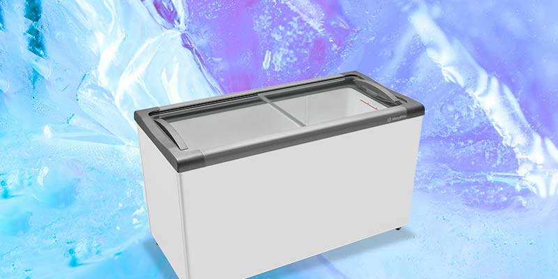 Freezer horizontal branco com tampa de vidro deslizante em destaque sobre um fundo artístico de cristais de gelo azuis e violetas.